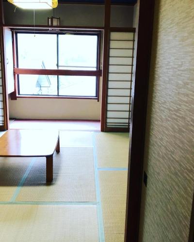 湯沢町にあるNAEBA KOGEN HOTELのテーブルと大きな窓が備わる客室です。