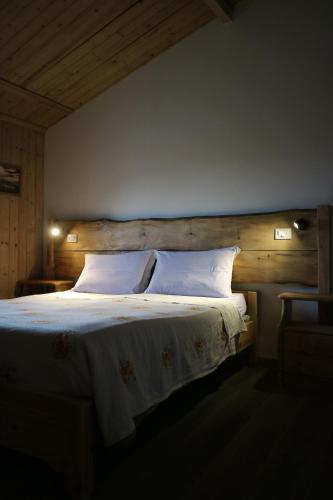 a bedroom with a large bed with a wooden headboard at Hotel Piccola Mantova in Bosco Chiesanuova