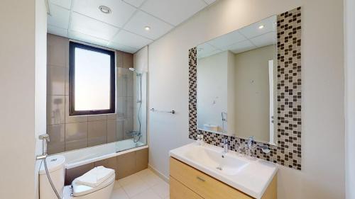 a bathroom with a sink and a toilet and a mirror at Primestay - Odora 6BR, Akoya Oxygen in Dubai