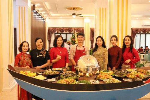 un grupo de personas de pie alrededor de un buffet de comida en Vsana Vu Son Hotel, en Sầm Sơn