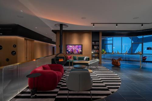 a living room with red chairs and a tv at CitiGO Hotel Shenzhen Shekou Cruise Center Seaview Near Taizi Bay K11 in Shenzhen