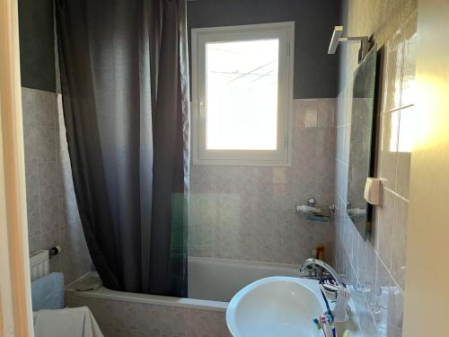 a bathroom with a sink and a tub and a window at Le Mans Kleber in Le Mans