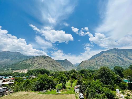 Bajaura的住宿－Hotel Anjum Regency，享有蓝天和云的山脉美景