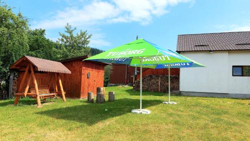 a green umbrella and a bench in a yard at PENSIUNEA BOCA VORONET in Voronet