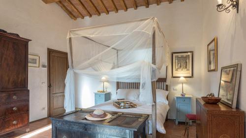 a bedroom with a canopy bed with a wooden table at CASALE MOLLINA 6&2, Emma Villas in Anghiari