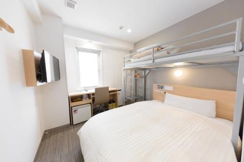 a bedroom with a bed and a desk and a television at Super Hotel Tokyo Otsuka in Tokyo