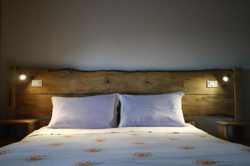a bed with two pillows and a wooden headboard at Hotel Piccola Mantova in Bosco Chiesanuova