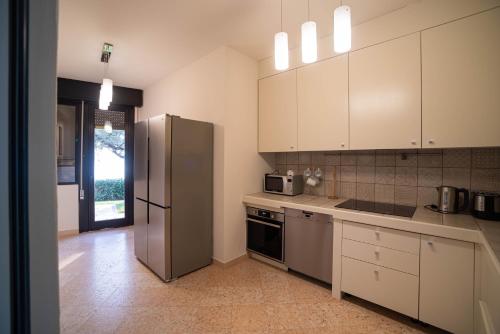 a kitchen with white cabinets and a stainless steel refrigerator at Villa Elysium in Torri del Benaco