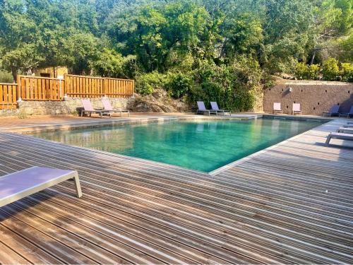 a swimming pool with chairs and a wooden deck at Camping Olva - Maeva in Sartène