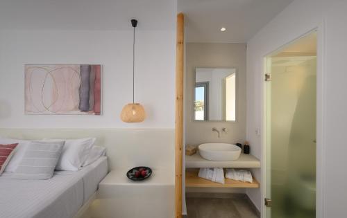 a white bedroom with a sink and a bed at Thoè Oia Suites in Oia