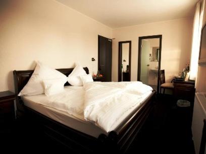 Schlafzimmer mit einem Bett mit weißer Bettwäsche und Kissen in der Unterkunft Althoff´s Landhotel in Ochtrup