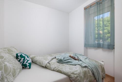 ein Bett mit einer Decke und einem Fenster in der Unterkunft Apartment KATI&ANA in Rijeka