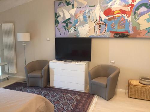 a bedroom with two chairs and a flat screen tv at Villa Elysium in Torri del Benaco