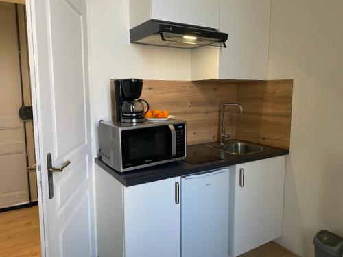 une petite cuisine avec un micro-ondes et un évier dans l'établissement Chez Tony, à Périgueux
