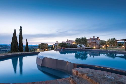 a large swimming pool with blue water in front of a house at Dimora Santa Margherita - Relais di Charme in Cinigiano