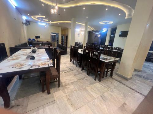 Bajaura的住宿－Hotel Anjum Regency，餐厅内带桌椅的用餐室