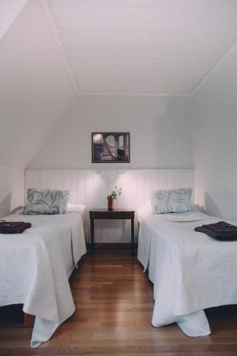 a room with two beds with white sheets and a table at Vääksyn Apteekinmajoitus in Vääksy