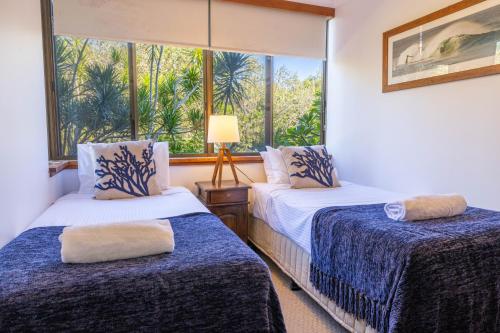 two beds in a room with a window at Coastal SOL -Right on Clarkes Beach! in Byron Bay