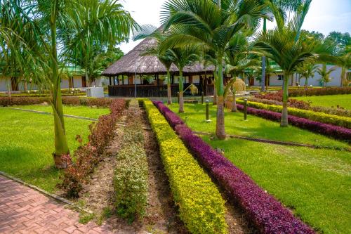 a garden with palm trees and flowers in front of a building at Grand Hotel Juba in Juba