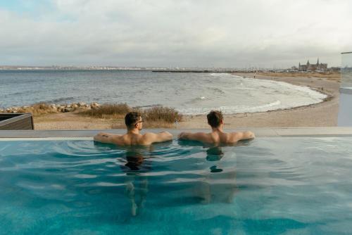 two men sitting in a swimming pool next to the beach at Marienlyst Strandhotel in Helsingør