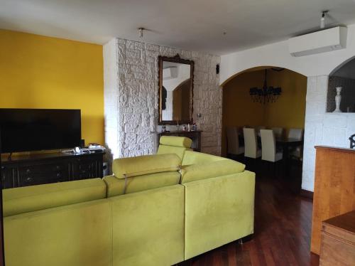 ein Wohnzimmer mit einem gelben Sofa und einem TV in der Unterkunft VILLA FOR RYDER CUP in Guidonia