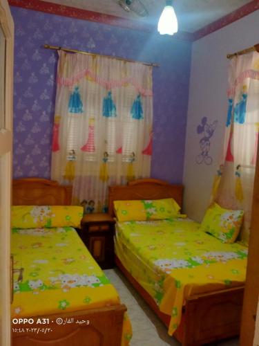 two beds in a room with purple walls and curtains at الوحيد برأس البر in ‘Izbat al Burj
