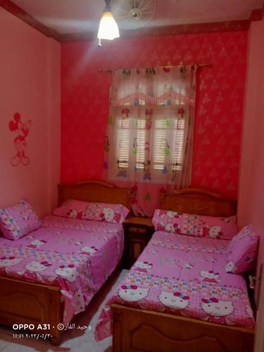 Duas camas num quarto com paredes cor-de-rosa em الوحيد برأس البر em ‘Izbat al Burj