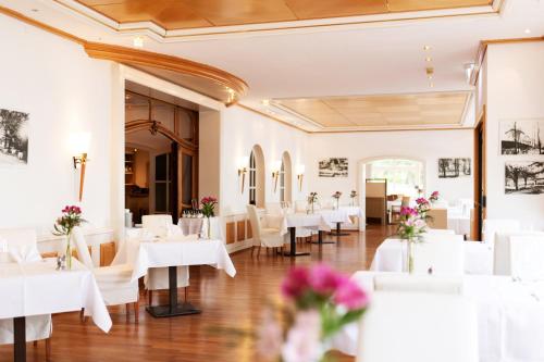 a dining room with white tables and white chairs at Hotel Dieksee - Collection by Ligula in Malente