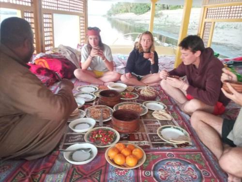 Eine Gruppe von Menschen, die auf einer Couch sitzen und Essen essen. in der Unterkunft Sailing boat in Assuan