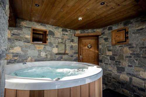 a large tub in a room with a stone wall at Les Chalets du Cocoon in La Plagne