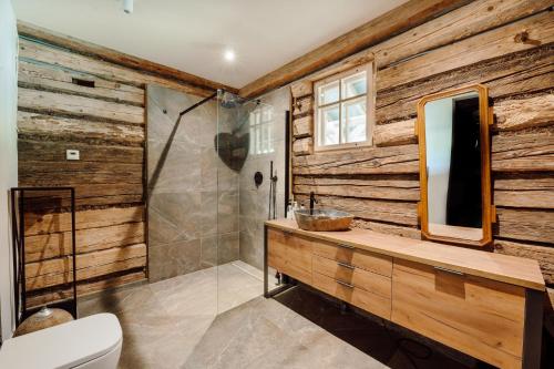 a bathroom with wooden walls and a sink and a mirror at Dom pod Lipami in Bachórz