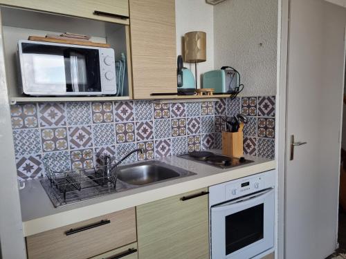 uma pequena cozinha com um lavatório e um micro-ondas em Duplex 2 chambres vue panoramique Mer em Le Barcarès
