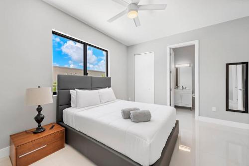 Granada Modern Luxury in Massive Mansion with Heated Pool في ميامي: غرفة نوم بيضاء مع سرير كبير ومروحة سقف