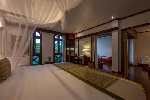 een slaapkamer met een groot wit bed en ramen bij La Résidence Phou Vao, A Belmond Hotel, Luang Prabang in Luang Prabang