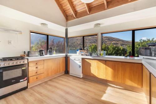 a kitchen with wooden cabinets and windows with a view at Small Wallet-Friendly Private Room in a 7 BR Shared House - The Ben's Room 6 in Queenstown