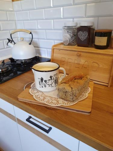 a cup of coffee and a loaf of bread on a cutting board at Szyszkowy Domek in Milejczyce