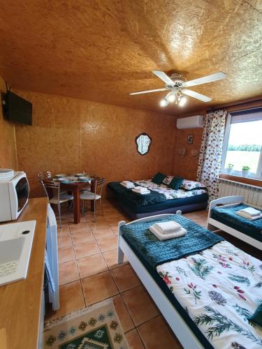 a room with two beds and a kitchen with a table at Szyszkowy Domek in Milejczyce