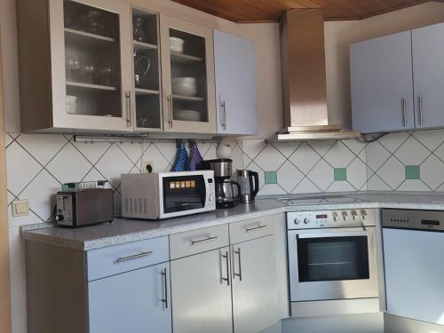una cocina con armarios blancos y electrodomésticos blancos en Ferienwohnung Deichblick en Gerhardshofen