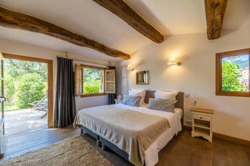 a bedroom with a bed and a large window at Hôtel du Domaine Casanghjulina in Porto-Vecchio