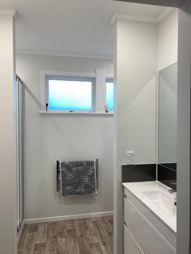 a white bathroom with a sink and a mirror at Lovely Newly Renovated Home in Hamilton