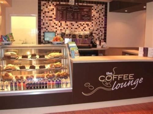 a coffee shop with a display case filled with pastries at P&T's Home from Home in Rhyl