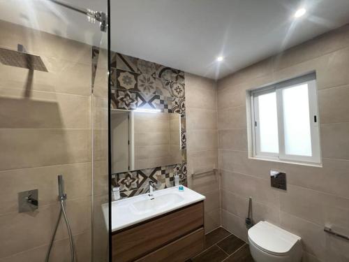 a bathroom with a sink and a toilet and a window at Zejtun 3-Bedroom Modern Apartment in Żejtun