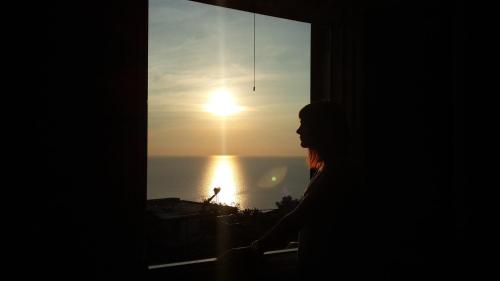 a man looking out a window at the sunset at Villa family Bitri in Piqeras