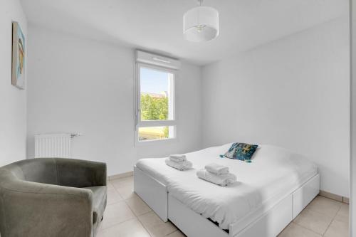a white bedroom with a bed and a chair at La Marquette - Appartement avec balcon in Toulouse