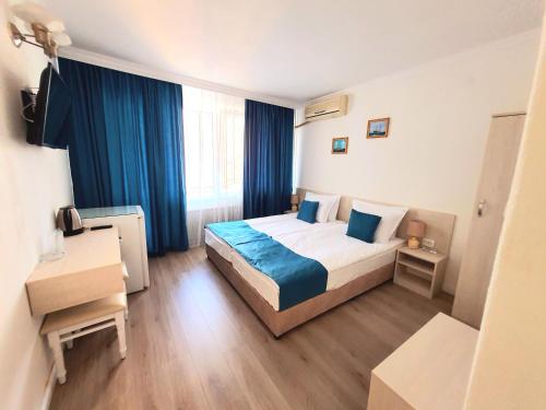 a hotel room with a bed and blue curtains at Guest House Kolev - central in Nesebar