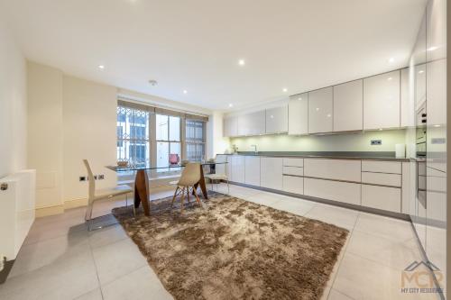 cocina con armarios blancos, mesa y alfombra en The Shepherd Residence en Londres