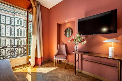 a bedroom with orange walls and a tv on the wall at Hotel Duomo Firenze in Florence