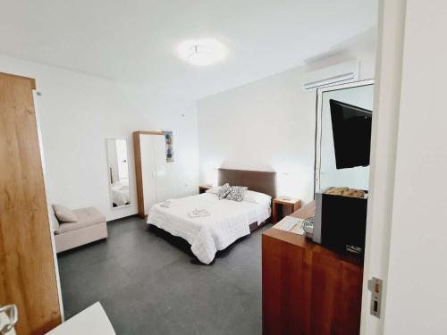 ein weißes Schlafzimmer mit einem Bett und einem Spiegel in der Unterkunft Medusa room apartment in Porto Cesareo