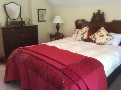 a bedroom with a bed with a red blanket on it at Secluded cosy cottage in Newbury