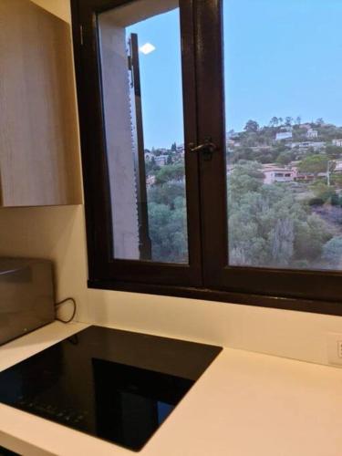 une cuisine avec une fenêtre offrant une vue sur la ville dans l'établissement Grand studio 35 m2 avec mezzanine et vue mer, à Théoule-sur-Mer